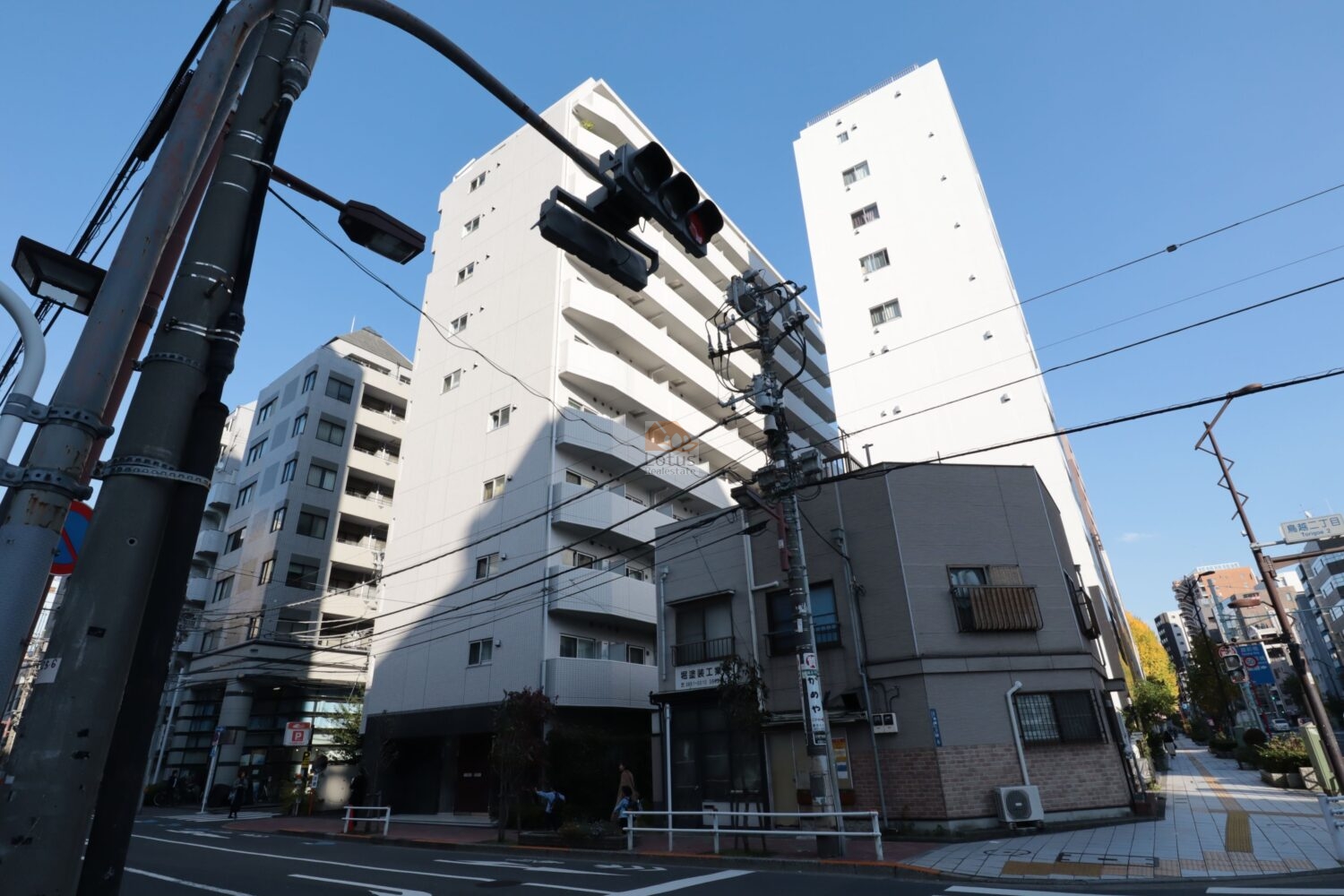 交差点に面した立地で、歩道が広く整備されているため人の動きが把握しやすいです。バルコニーが連続する白基調の外壁が採用され、全体に整ったラインが見えます。周囲には低層〜中層の建物が多く、街区内で視界が開ける方向がある点も利便性に寄与しています。