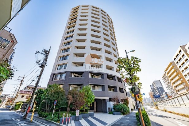 円弧を描くような外観フォルムが、交差点角地で自然に視線を集めます。高さのある建物ですが、足元の植栽が道路との距離感を和らげ、国道131号（産業道路）沿いでも圧迫感は抑えられています。交通量の多さは感じつつも、都市型レジデンスとして整理された存在感です。