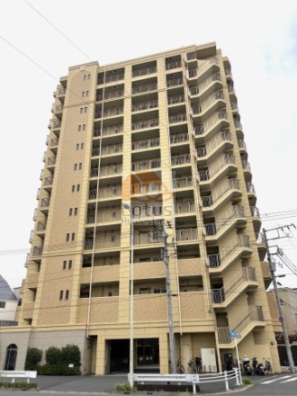 交差点角地に建つ12階建ての量感ある外観。淡いベージュ系タイルと縦ラインが、街並みに整った輪郭と落ち着きを与えています。