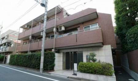 サニーコート沼袋_外観2｜サニーコート沼袋の外観は、タイル貼りの低層3階建てで、落ち着いた街並みに馴染むブラウン系の外壁が特徴です。道路に面した植栽や電柱、ファサードの水平ラインが整い、静かな住宅街の一角に佇みます。